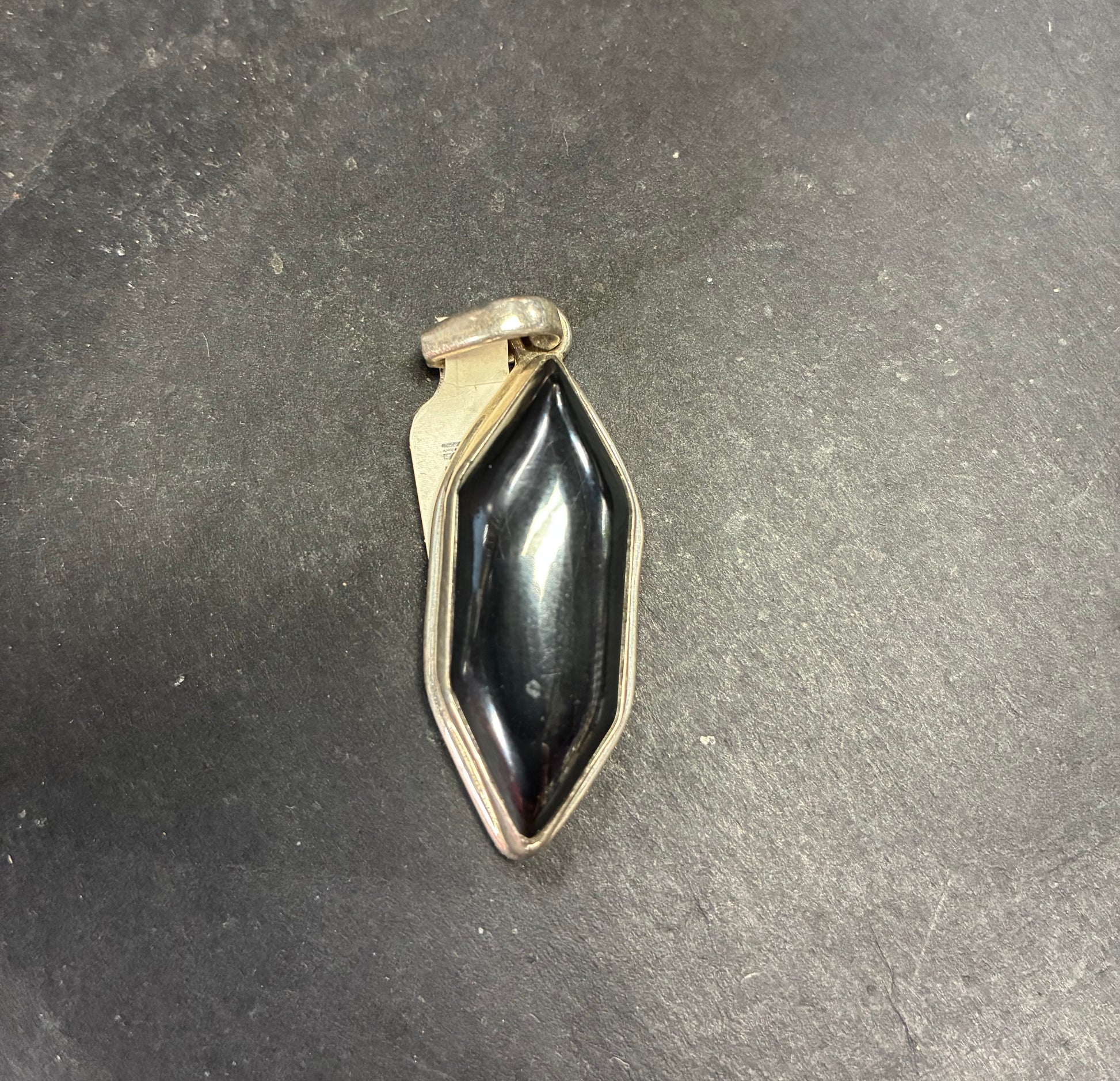 Black stone pendant on a dark gray surface