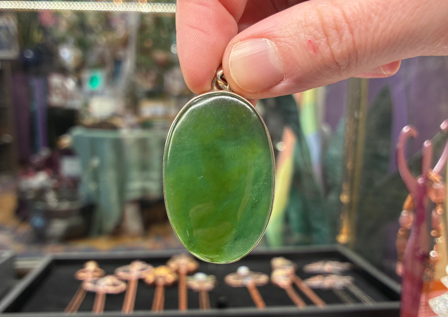 Hand holding a green pendant with a blurred background