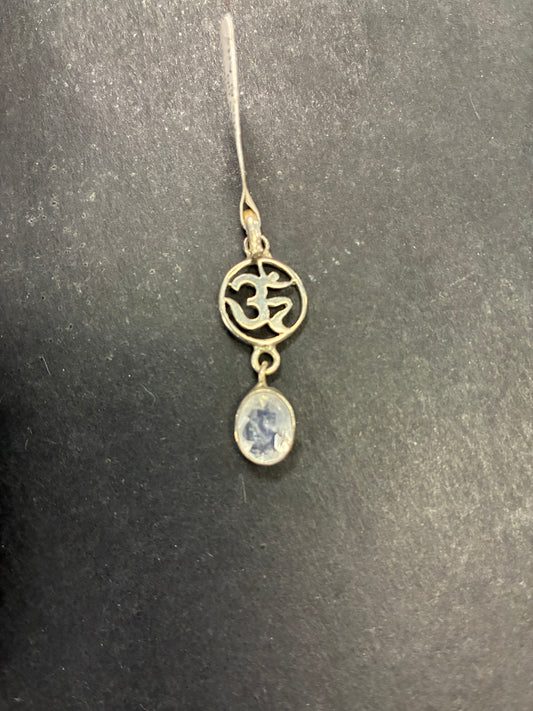 Jewelry pendant with Om symbol and blue stone on a dark background