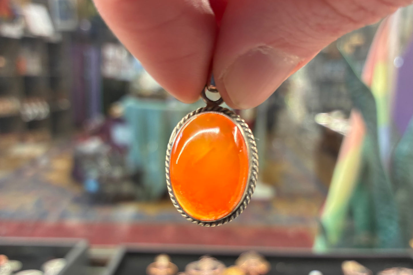 Hand holding an orange pendant with a blurred background