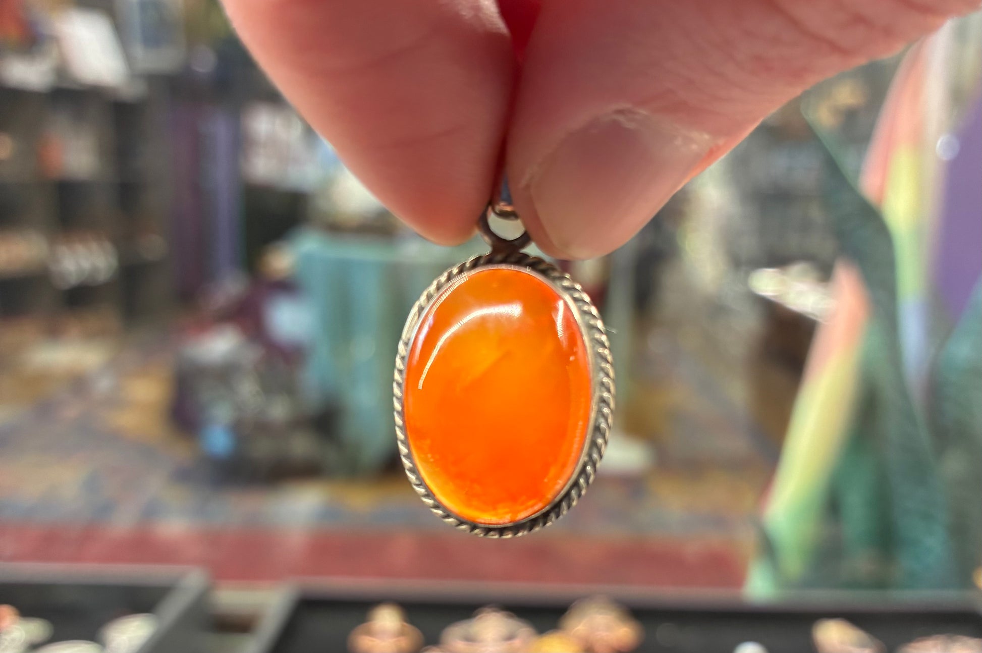 Hand holding an orange pendant with a blurred background