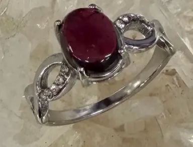 Silver ring with a red gemstone on a light background
