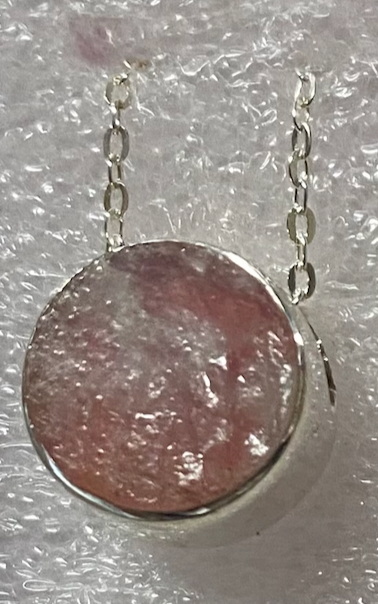 Necklace with a pink stone pendant on a textured surface