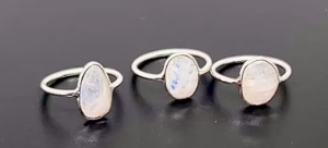Three silver rings with opal stones on a black background