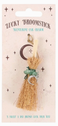 A 'Lucky Broomstick' adventine car charm by The Sweet A Day, shown on its original backing card. The charm features a miniature straw broom with a green leaf accent, a silver crescent moon, and a gold loop at the top.