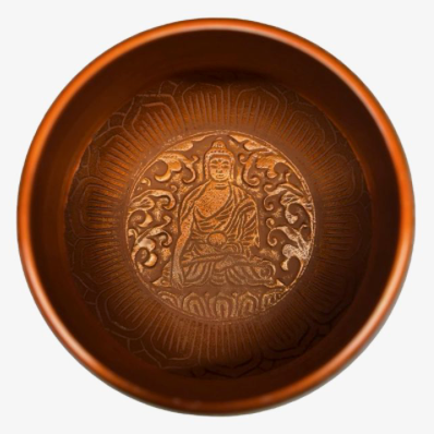 A round copper-colored bowl with a detailed relief carving of a seated Buddha figure on the inside, shown against a plain white background.