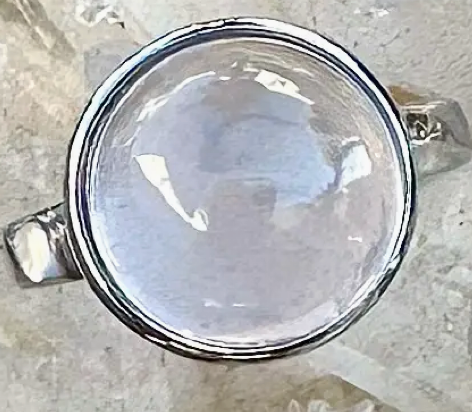 Silver ring with a rose quartz on a textured surface