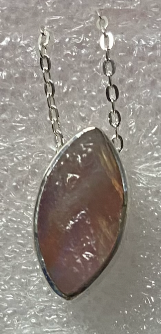Necklace with a large, faceted stone pendant on a textured gray background