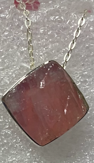 Necklace with a pink stone pendant on a textured surface