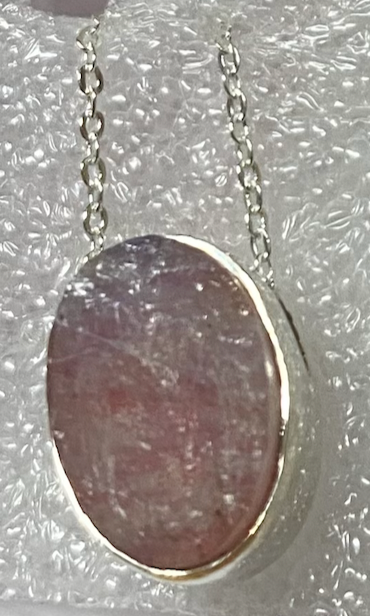 Necklace with a pink stone pendant on a textured gray background