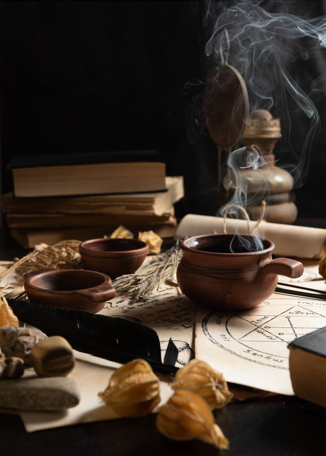 Magical or ritualistic setup with books, a pentagram, and smoking objects on a dark background