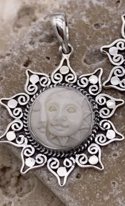 Silver pendant with intricate designs on a textured surface