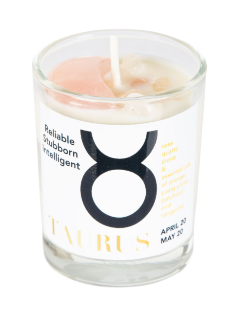 Candle in a glass jar with a Taurus zodiac symbol and descriptive text on a white background