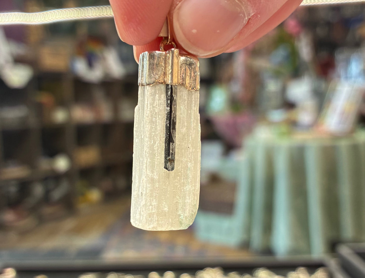 Crystal pendant held by a hand with a blurred store background