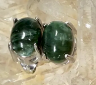 Green gemstones in silver settings on a white background