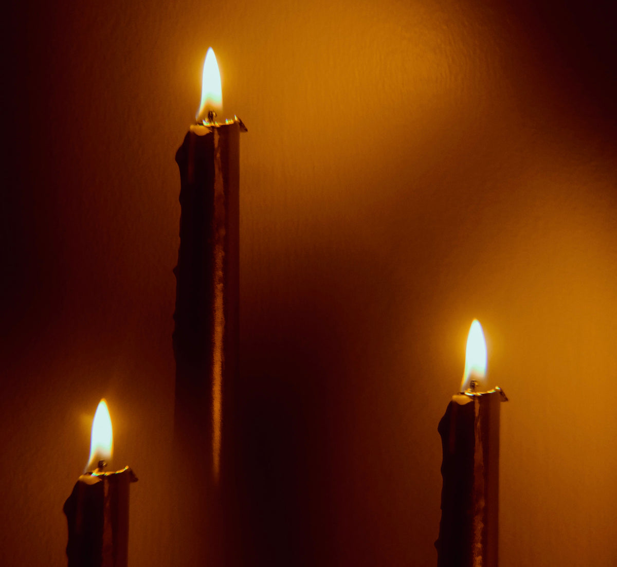 Three floating lit candles with a dark background