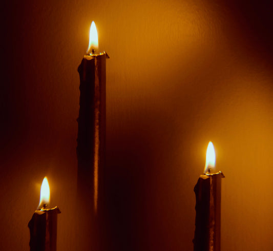 Three floating lit candles with a dark background