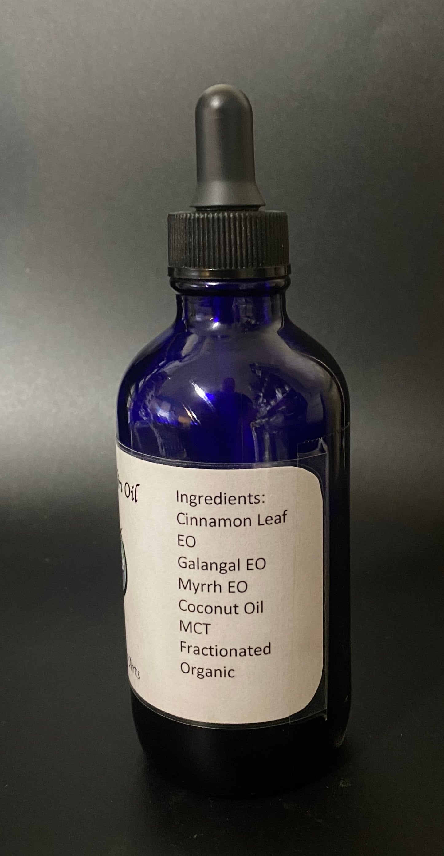 Blue glass bottle with dropper labeled with ingredients on a dark background