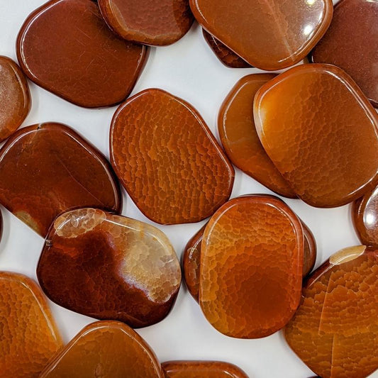 Flat oval shaped semi-translucent stones in red, orange, and yellow  with quartz spots