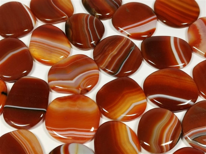 flat, polished, oval pieces of red and orange stones with white stripes in various sizes