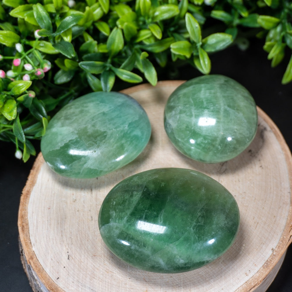 smooth polished palm sized ovular stones in varying shades of green, turquoise, and purple