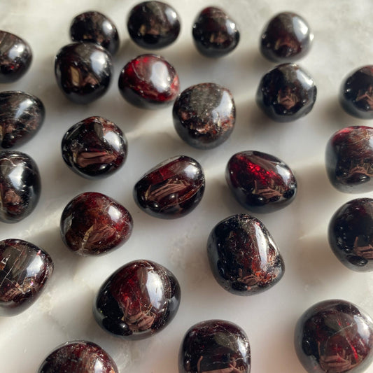 tumbled dark red almost black stones in varying shades, semi-translucent and very red in some places.