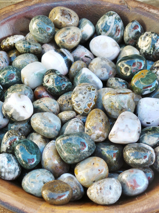 tumbled smooth stones in a variety of colours, including orbs and spots of red, grey, pink, yellow blue, and green, usually on a base of white, green, or grey.