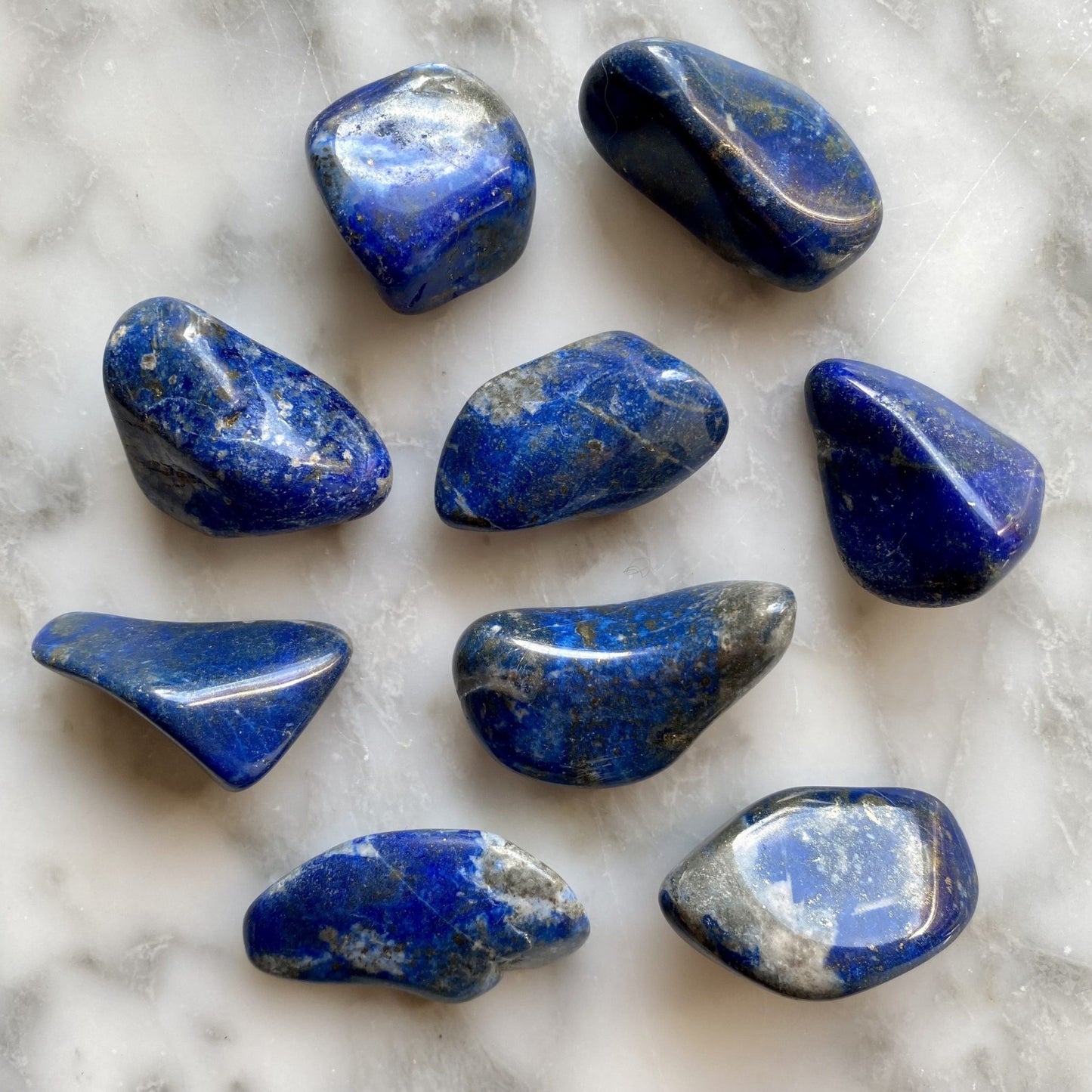 Dakr blue stones, tumbled, smooth, with grey spots and gold specks.